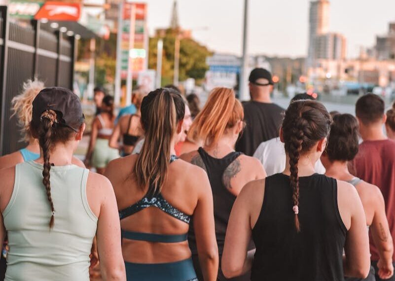 A group of adults walking outdoors during sunset in a city setting, focused on fitness and health.